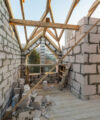 House interior under construction and renovation. Energy saving walls of hollow foam insulation blocks and bricks, ceiling beams and roof frame.