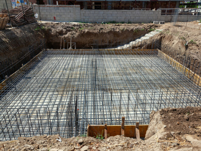Foundation reinforcement with steel rebar grid, preparing for concrete pouring at building construction site
