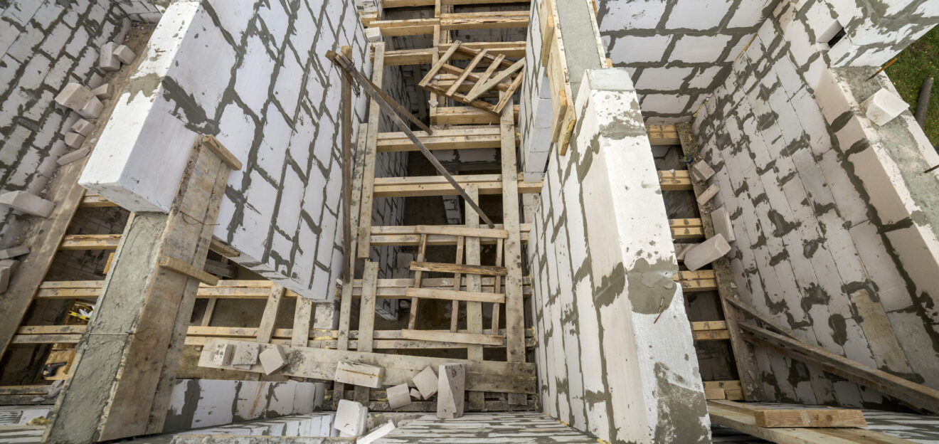 View from above of future multi stored cottage energy saving walls of large white hollow foam insulation blocks and temporary wooden scaffolding frame. Construction masonry, modern technology concept.