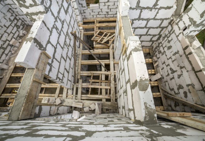 View from above of future multi stored cottage energy saving walls of large white hollow foam insulation blocks and temporary wooden scaffolding frame. Construction masonry, modern technology concept.