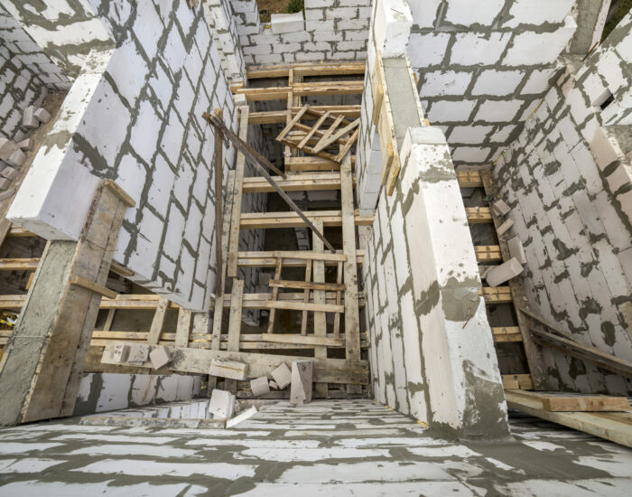 View from above of future multi stored cottage energy saving walls of large white hollow foam insulation blocks and temporary wooden scaffolding frame. Construction masonry, modern technology concept.